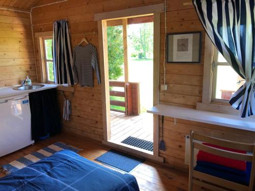 a wooden cabin with a kitchen and a door to a porch at Merejussi Puhkemajad in Pärna