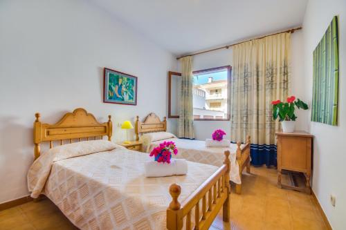 a bedroom with a bed and a table with flowers on it at Ideal Property Mallorca - Villa Rosita 12 in Alcudia