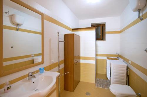 a bathroom with a sink and a toilet and a mirror at Costiera del Cilento Apartments in Casal Velino
