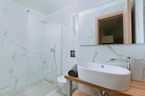 W białej łazience znajduje się umywalka i lustro. w obiekcie Summer Feelings w mieście Skála Sotíros