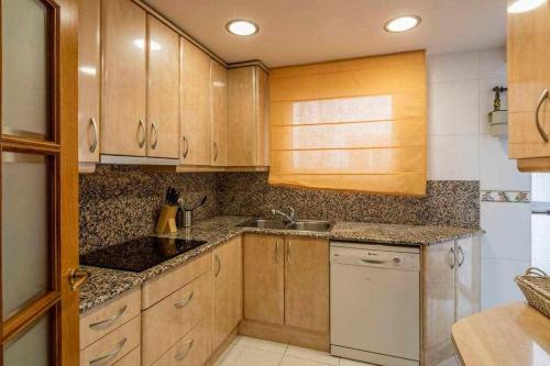 a kitchen with wooden cabinets and a sink at Ático con gran terraza en el corazón de Girona in Girona