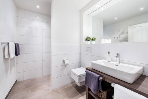 a white bathroom with a sink and a toilet at Weisse Villa Apartment 3 2 Annis Strandnest in Büsum