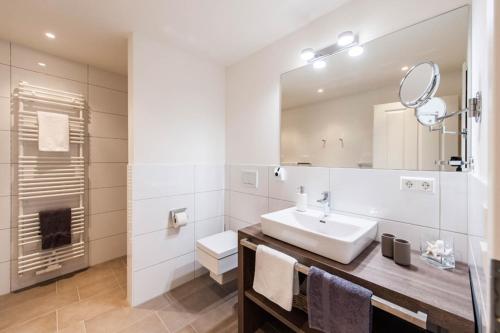 Baño blanco con lavabo y espejo en Weisse Villa Apartment 2 4 Estelles Beachhouse en Büsum