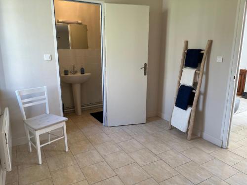 een badkamer met een deur, een stoel en een wastafel bij Maison au coeur du Morvan in Arleuf