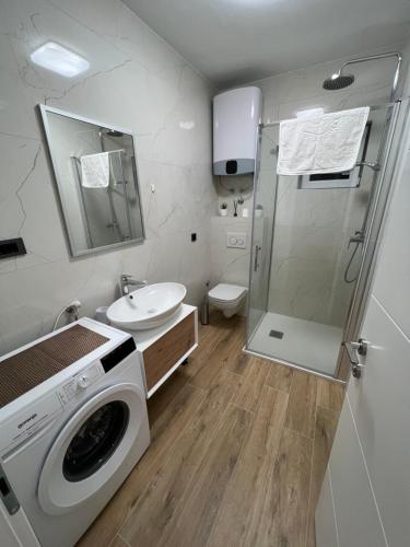 a bathroom with a washing machine and a sink at Apartman Oneum in Omiš