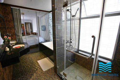 a bathroom with a shower and a sink and a tub at Mercury Central Hotel Hanoi in Hanoi