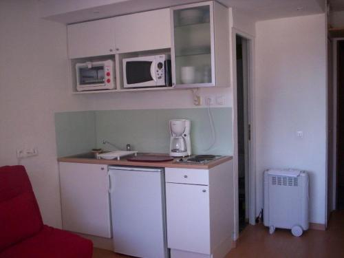a small kitchen with white cabinets and a microwave at Studio Plagne Bellecôte, 1 pièce, 2 personnes - FR-1-181-2234 in La Plagne Tarentaise