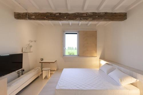 La Pervinca - Ospitalità, Natura, Cura في غواستالا: غرفة نوم بيضاء فيها سرير وتلفزيون
