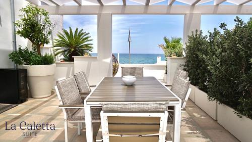 a wooden table and chairs on a patio with the ocean at La Caletta Suite Torre Canne in Torre Canne