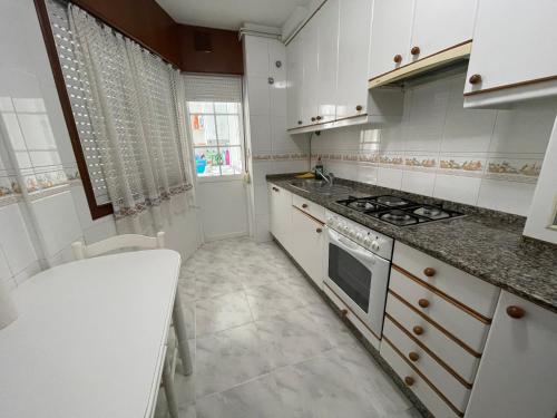 uma cozinha com armários brancos e um forno com placa de fogão em Oktheway Miño Little Beach em Miño