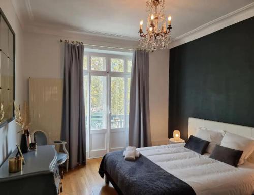 a bedroom with a large bed and a chandelier at Le Ness - Face au Pont des Amours - Majord'Home in Annecy