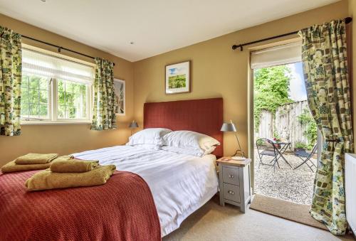 a bedroom with a bed and a sliding glass door at Jasmine Cottage in Iwerne Minster