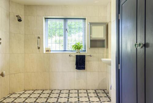 a bathroom with a shower with a sink and a window at Jasmine Cottage in Iwerne Minster