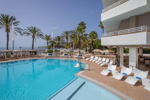 a pool at the resort with chairs and palm trees at Sol House The Studio - Calviá Beach - Adults Only in Magaluf