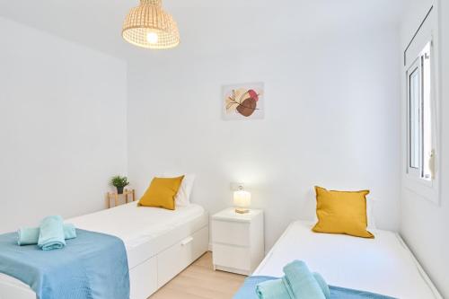two beds in a room with white walls and yellow pillows at Lovely 2 bedroom apartment with terrace in Blanes
