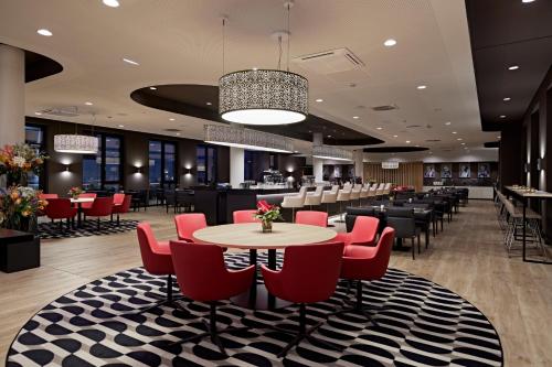 a restaurant with red chairs and tables and a bar at LÉGÈRE HOTEL Erfurt in Erfurt