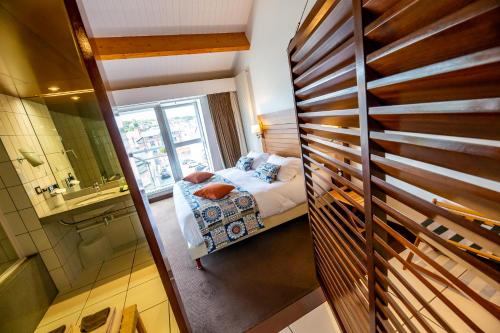 a small bedroom with a bed and a bathroom at Hotel Le Grand Pavois in Fécamp