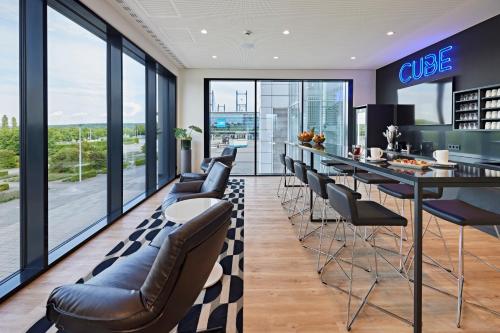a bar with leather chairs and a counter in a room with windows at LÉGÈRE HOTEL Erfurt in Erfurt