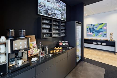 a restaurant with a counter with a coffee shop at LÉGÈRE HOTEL Erfurt in Erfurt