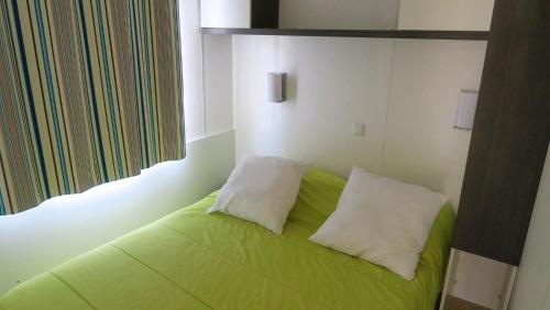 1 cama verde con 2 almohadas en una habitación en Camping Le Bouloc en Ceilhes-et-Rocozels