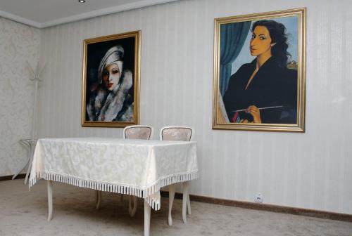 a table in a room with two paintings on the wall at Hotel Dunav Požarevac in Požarevac