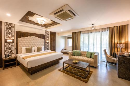 达曼Silver Waves Resort & Spa - Daman的一间卧室，里面有一张床、一张沙发和一张桌子