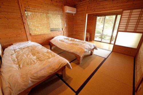 a bedroom with two beds in a wooden cabin at 一棟貸　屋久の子の家 in Yakushima