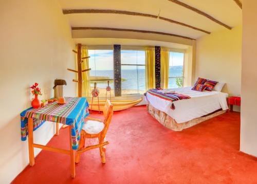 a bedroom with a bed and a desk with a table at titicaca lodge - LUQUINA in Luquina