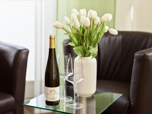 a bottle of wine and a vase of white flowers on a table at Kettern Urlaub in Piesport