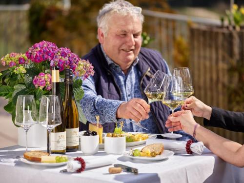 un uomo e una donna più grandi seduti a un tavolo con bicchieri da vino di Kettern Urlaub a Piesport