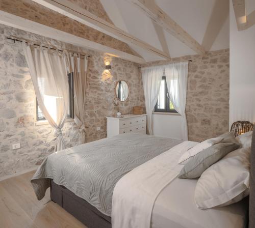 a bedroom with a large white bed with stone walls at Casa M Hvar in Zastražišće