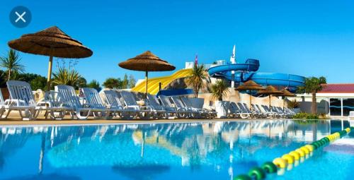 - une piscine avec des chaises et un toboggan dans l'établissement mobilhome 741 Les Charmettes,3ch,2sdb,lave linge,lave vaisselle,clim,2wc, aux Mathes