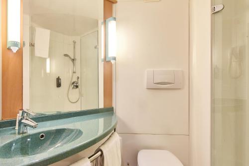 B&B HOTEL Paris Nord 2 CDG Aéroport في رواسي أون فرانس: حمام مع حوض أخضر ومرحاض