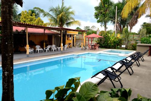Una gran piscina con sillas y una casa. en Cabañas Yakuruna, en Leticia