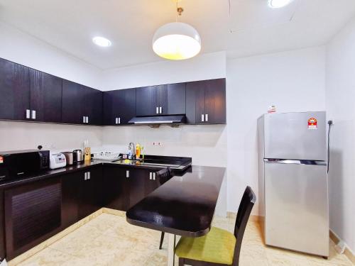 a kitchen with wooden cabinets and a stainless steel refrigerator at 【Amazing】Pool View 2BR Suite @ Pulai Springs Resort in Skudai