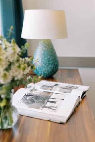a table with a magazine and a lamp on a table at The Editory Artist Baixa Porto Hotel in Porto
