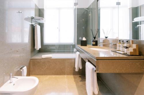 a bathroom with a sink and a tub and a toilet at The Editory Artist Baixa Porto Hotel in Porto