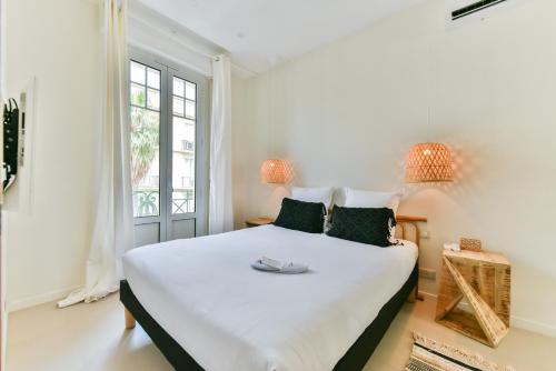 - une chambre dotée d'un grand lit avec des draps blancs et des oreillers verts dans l'établissement Bel appartement Juan-Les-Pins - 300m Plage, à Juan-les-Pins