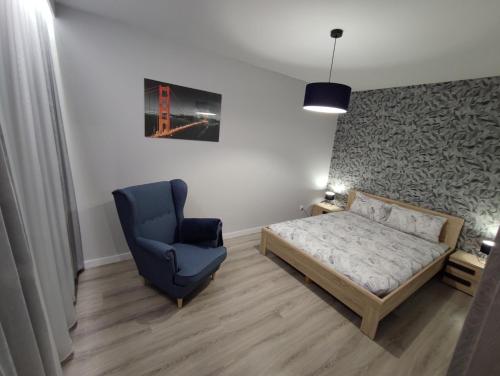 um quarto com uma cama e uma cadeira azul em Apartament Bukowy em Wejherowo