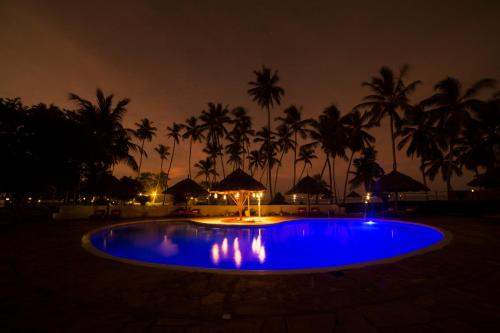 a pool at night with palm trees in the background at Antonio Beach Tree House Hotel & Spa in Uroa
