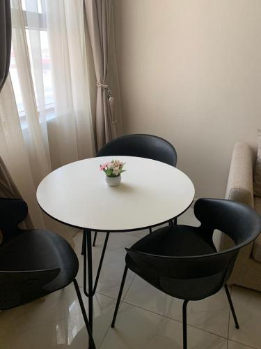 uma mesa branca e cadeiras com um vaso de flores em روز للشقق الفندقية 2 em Al Kharj