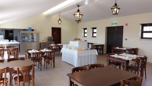 ein Restaurant mit Tischen und Stühlen und eine Küche in der Unterkunft HI Alfeizerão – Pousada de Juventude in Alfeizerão