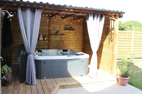 a hot tub on a wooden deck with curtains at le coin des hirondelles in Pontorson