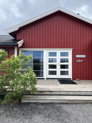 a red building with a white door and a porch at Toppøy Rorbuer in Reine