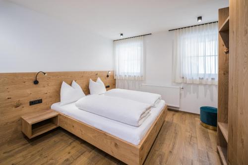 a bedroom with a large bed with white sheets at Kuenz Dolomites App 5 in San Candido