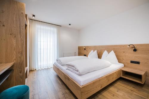 a bedroom with a large white bed with a wooden headboard at Kuenz Dolomites App 3 in San Candido
