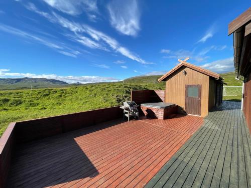 a wooden deck with a bench and a building at Dalsmynni in Blaskogabyggo