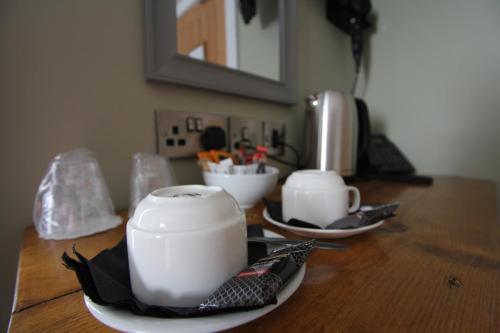 a wooden table with two cups and plates on it at Tyr Winch in Cardiff