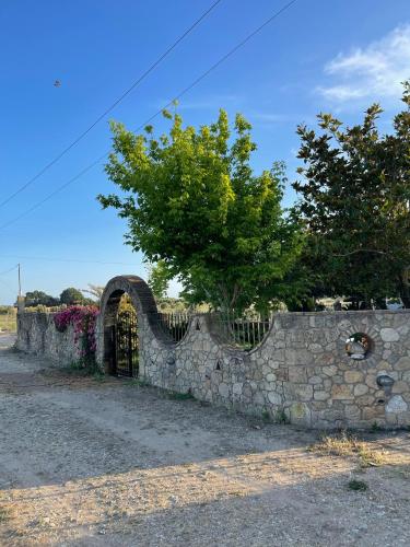 a stone wall with a gate and a tree at Mama’s Sunshine Garden Villa in Áyios Ilías
