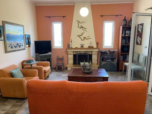 a living room with orange furniture and a fireplace at Mama’s Sunshine Garden Villa in Áyios Ilías